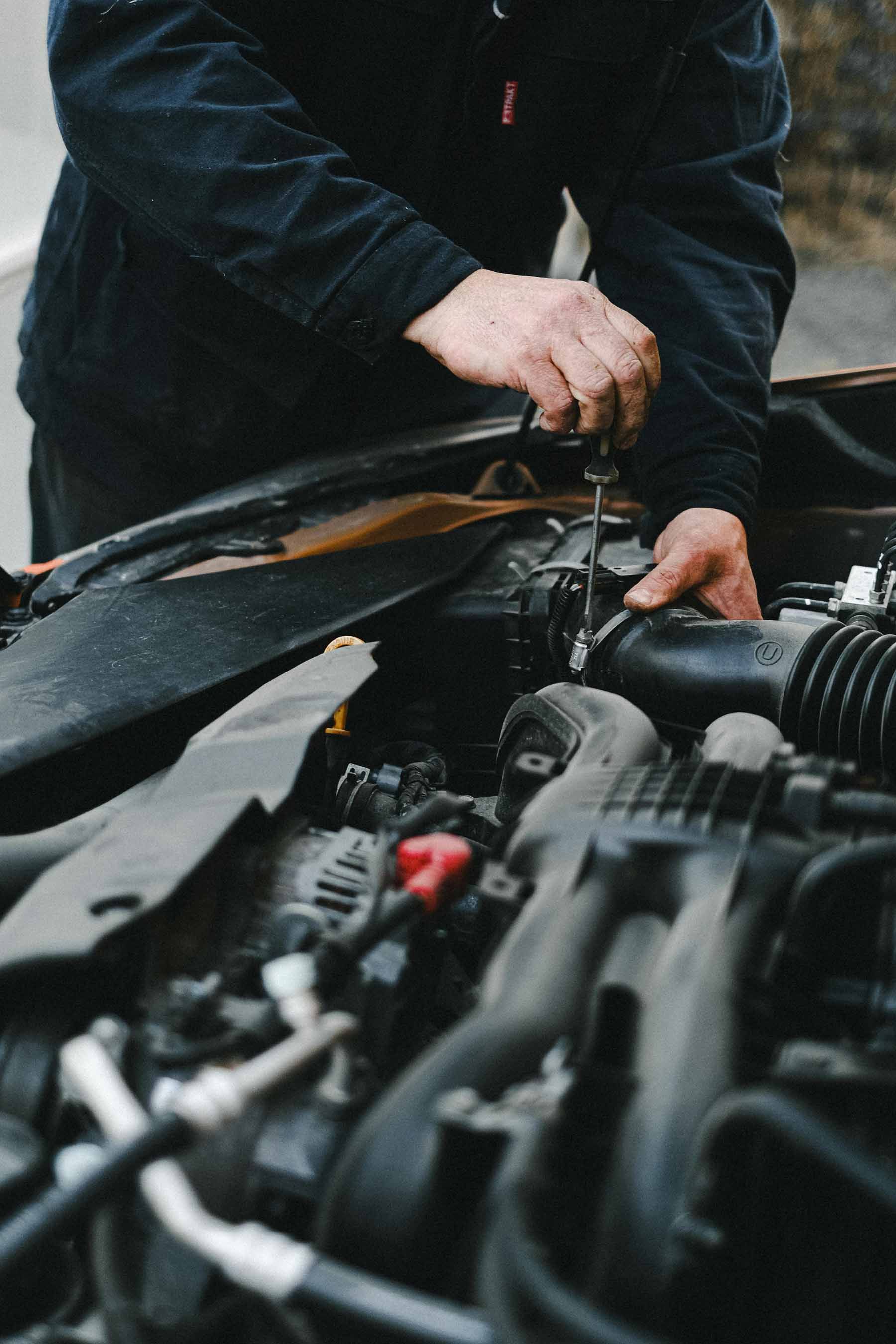 Mécanicien effectuant la réparation d’un moteur automobile au Garage Majestic SA à La Tour-de-Trême, entretien et service toutes marques.